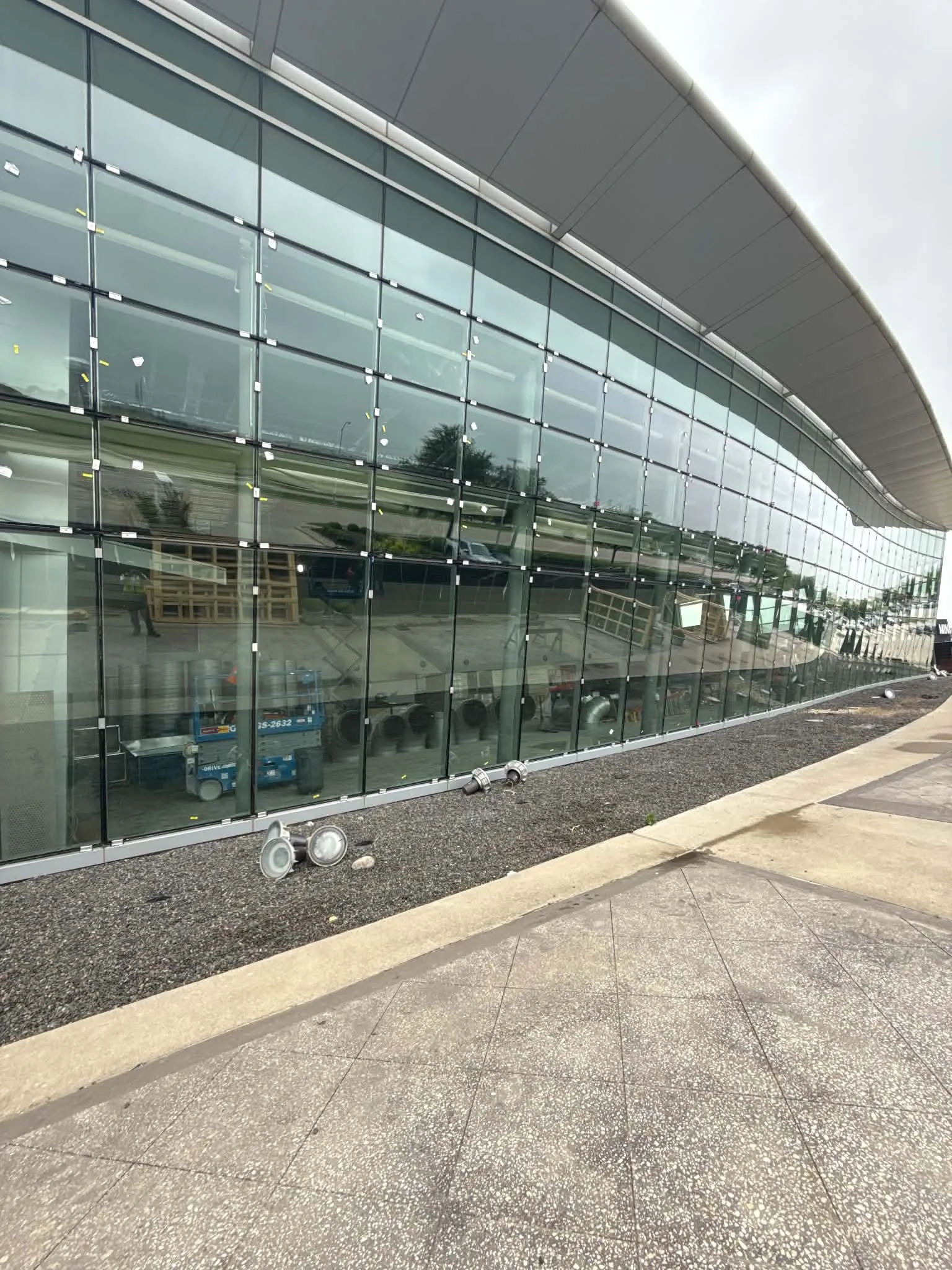 Reflective glass façade with a curved roofline during installation